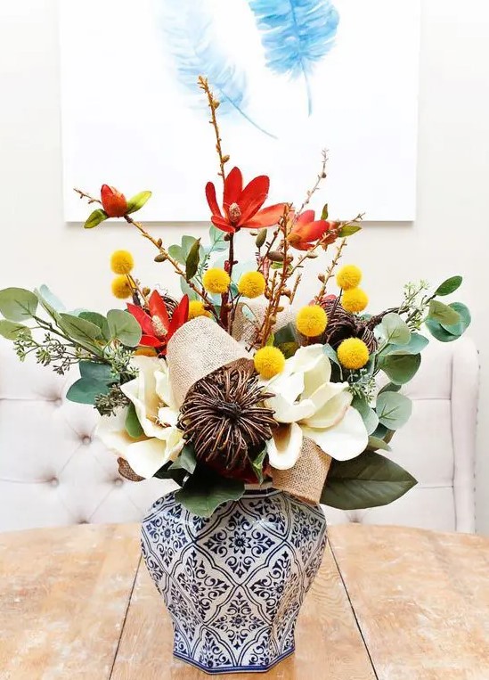 An elegant fall arrangement of leaves, Christmas balls, vines, burlap and artificial white flowers makes a great decoration