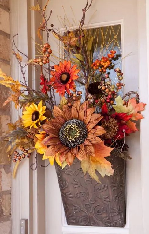 A pretty fall artificial flower arrangement with leaves, berries and twigs in traditional fall colors replaces a regular wreath