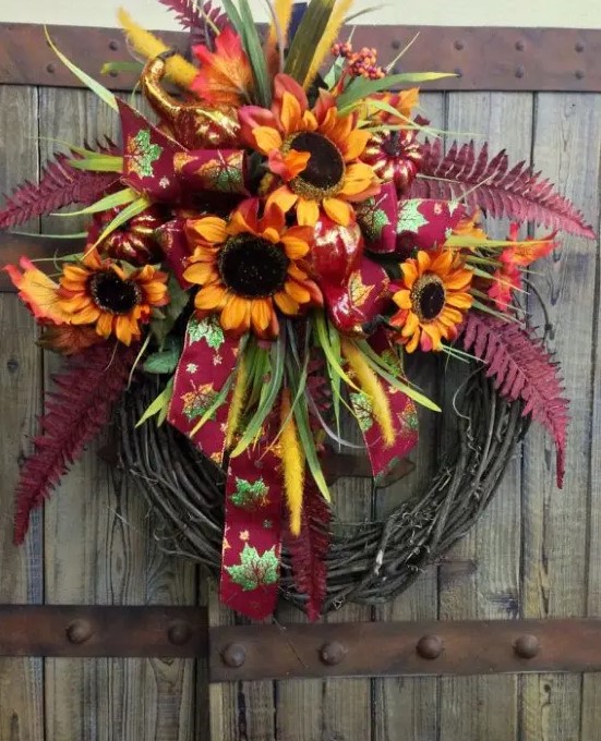 A fall wreath with bright faux blooms, leaves, and ribbons is a stylish and long-lasting outdoor decoration with a rustic feel