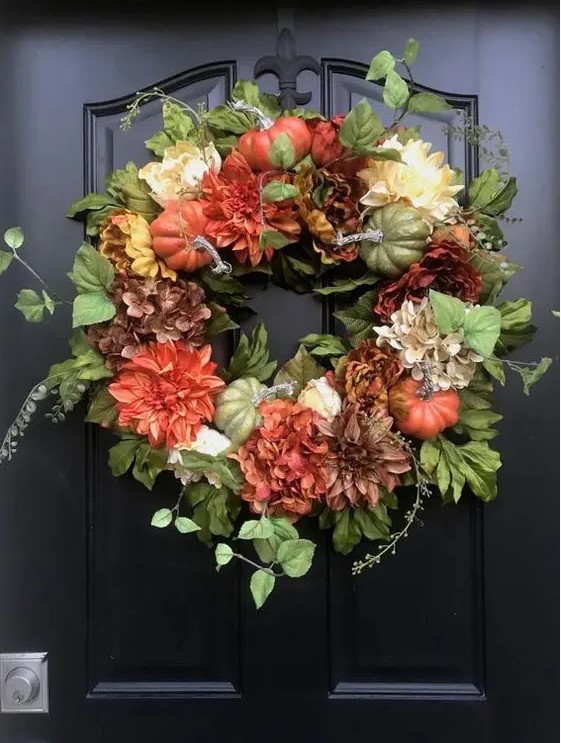 A stylish fall wreath made with greenery, faux pumpkins, and bright blooms is a cool decoration to rock