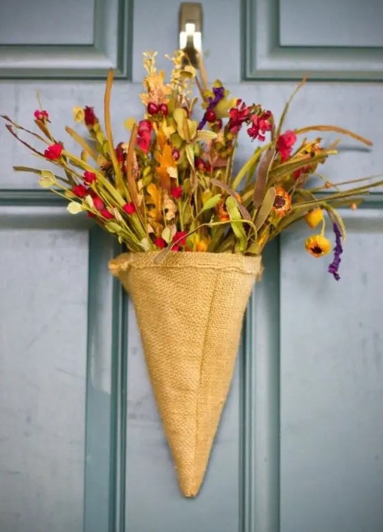A rustic door arrangement made from a burlap cone, artificial flowers and greenery is a beautiful alternative to a regular door wreath