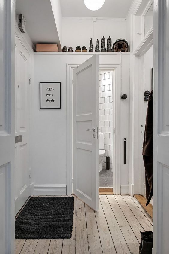 A small white entryway with an over-the-door shelf for storing boots and shoes is a clever and cool idea to organize a space