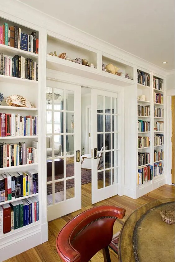 An entire wall taken up by lots of open bookcases on the sides and above the door, with a glass French door is a cool idea to store books and do it in style