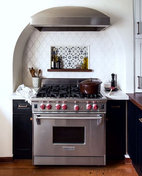 an arched niche with creative tiles and a cooker plus two narrow cabinets on both sides and a hood is a lovely idea for a modern kitchen