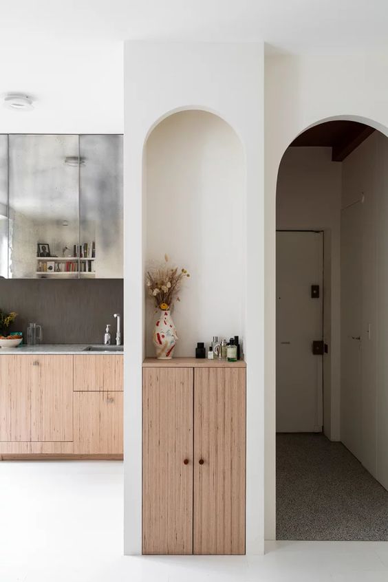 a tall and narrow arched niche with a small cabinet built-in and some decor is a lovely idea to use that awkward nook you might have in your space