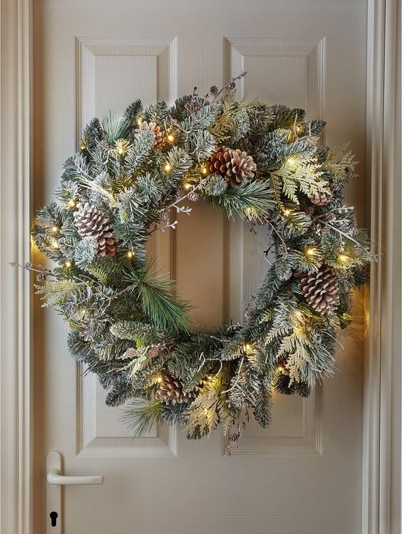 A beautiful flocked Christmas wreath with lights, branches and pine cones makes a lovely winter decoration