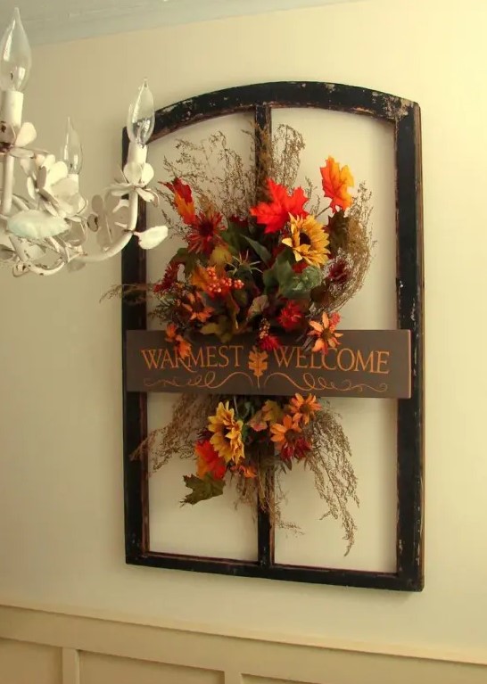 a vintage inspired faux floral decoration with branches, grasses and leaves in a frame and with a sign