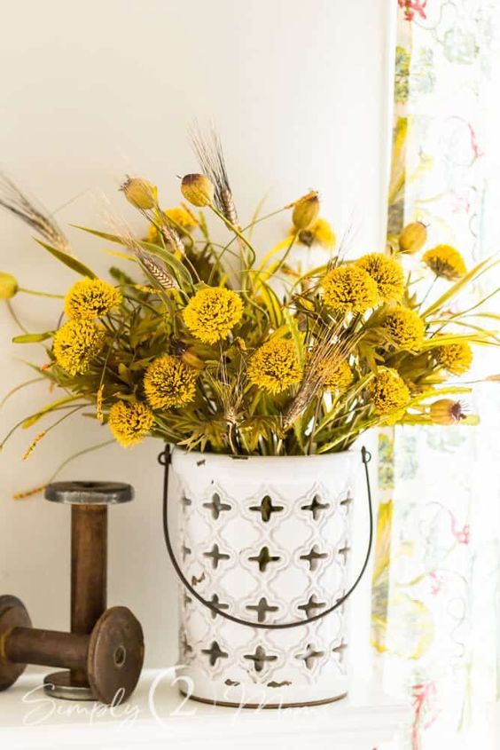 A mustard and yellow artificial flower arrangement with seed pods is a cool idea for fall decor
