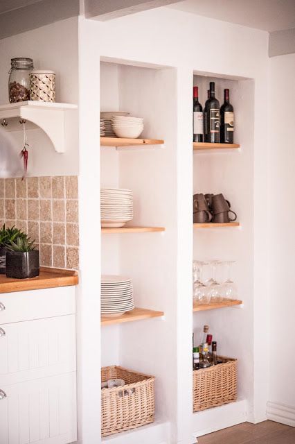 tall niches with timber shelves and baskets are used for storing dishes, glasses and wine are a great alternative to an upper row of cabinets