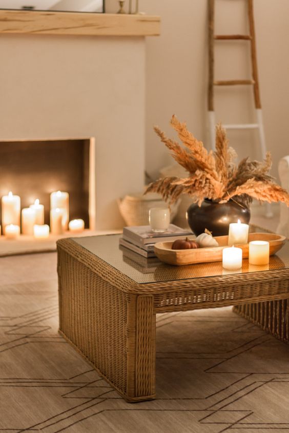 A boho room with a faux fireplace with candles, a wicker table with candles, and boho fall decor is cozy and inviting