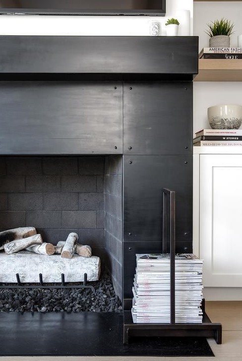 a black metal fireplace boasting a black hearth and a black mantel fixed beneath a television