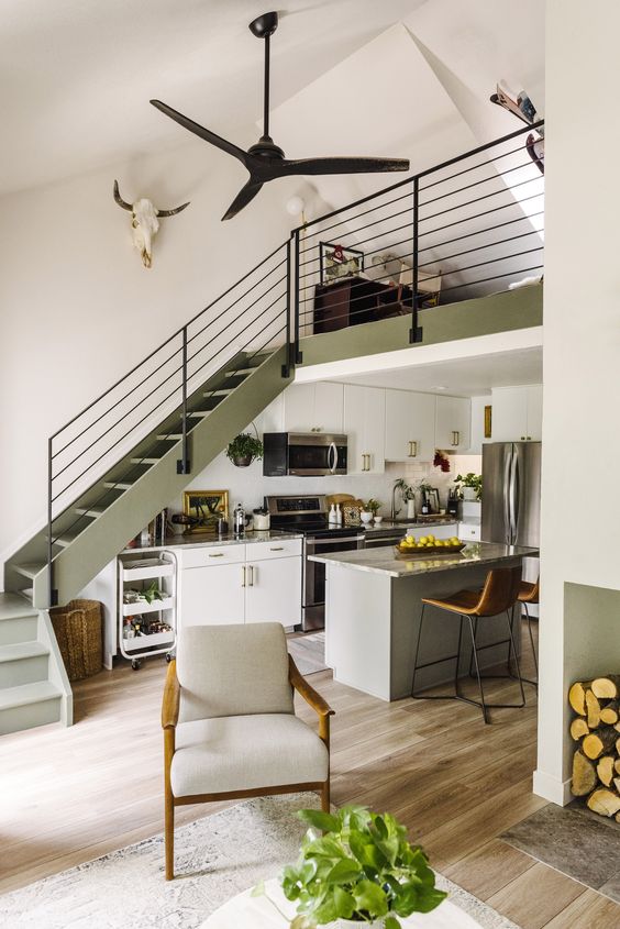 a catchy space with an olive green stairscase, cabinets and a grey kitchen island, stone countertops and built-in lights