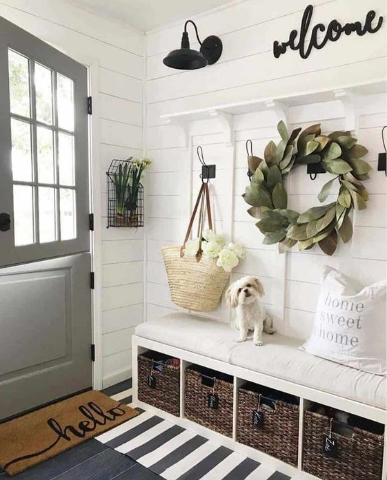 a chic neutral space with a leaf wreath, layered rugs, a built-in bench with baskets and some signs