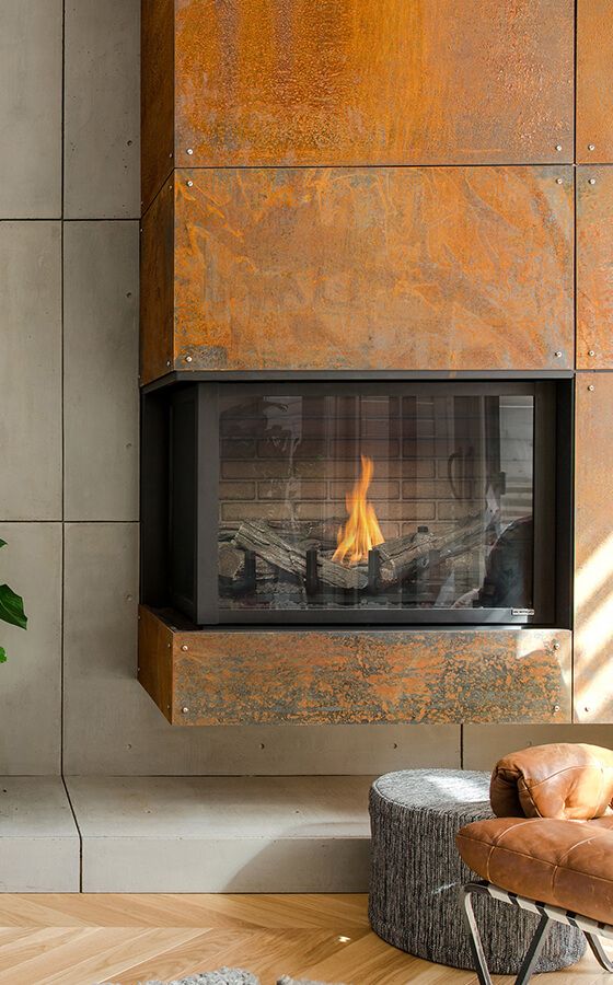 a copper clad built-in fireplace, a leather chair and a pouf compose a super cozy and welcoming nook
