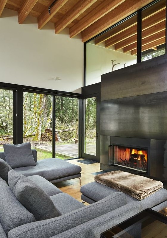 a fireplace clad with blackened steel separates the living room from the covered patio and brings coziness to the space