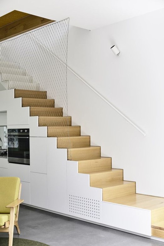 a minimalist white kitchen completely built into the staircase is a smart solution if you don't have space for a kitchen