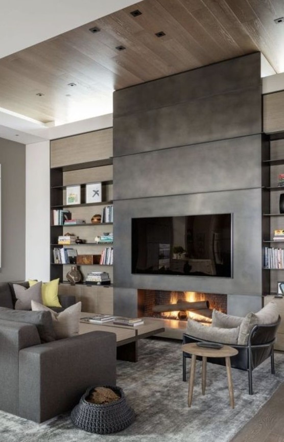 a modern living room done in all shades of grey, with a low coffee table, a fireplace clad with metal and a TV over it
