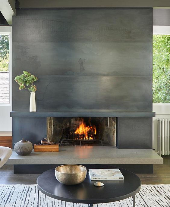 a modern living room with a metal clad fireplace, a coffee table and some decor is an airy space
