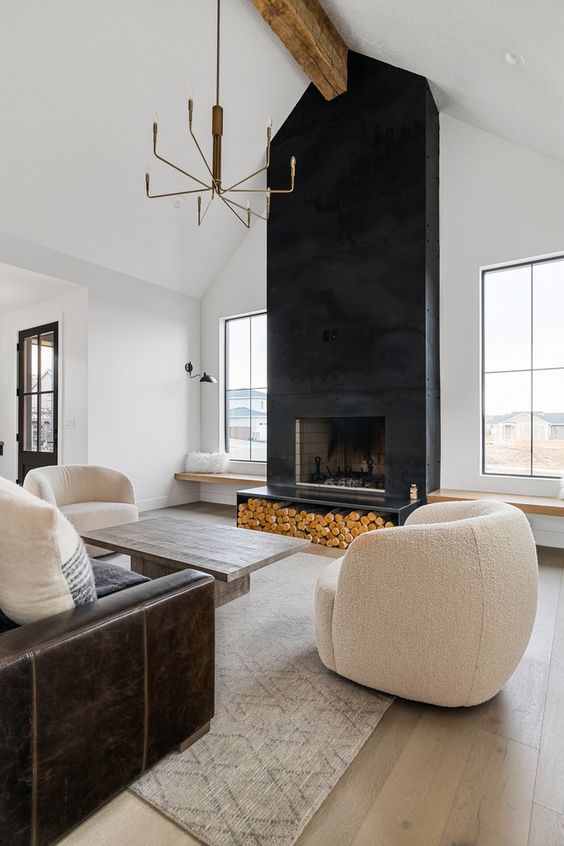 a neutral living room with a statement black metal fireplace, neutral seating furniture, a coffee table, a chandelier