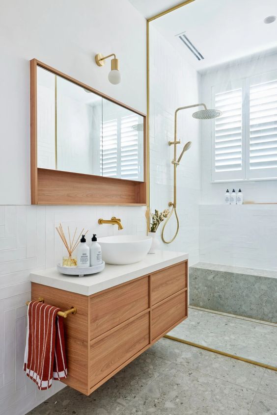 a pretty modern bathroom clad with white tiles and green terrazzo, a stained vanity, a mirror cabinet, gold fixtures is amazing