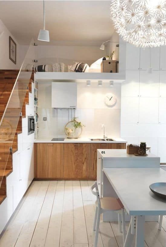 a small modern loft with a staircase as a built-in storage unit, stained cabinets, a hood and a kitchen island with a table