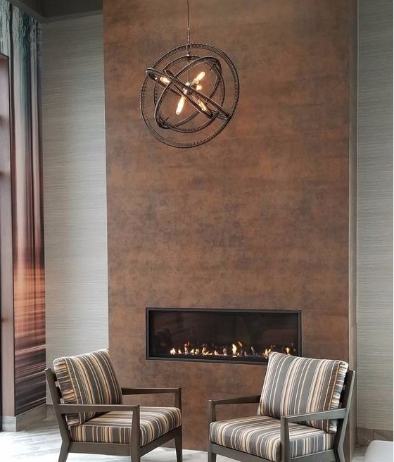 a stylish modern living room with a built-in fireplace clad with copper and a metal sphere chandelier looks very cool