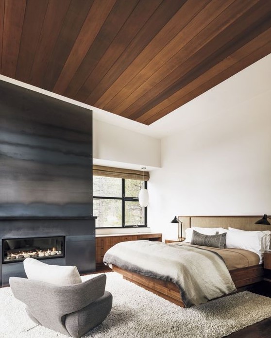 a sytlish contemporary bedroom with a large built-in fireplace surrounded with grey steel sheets for a slight chalet feel