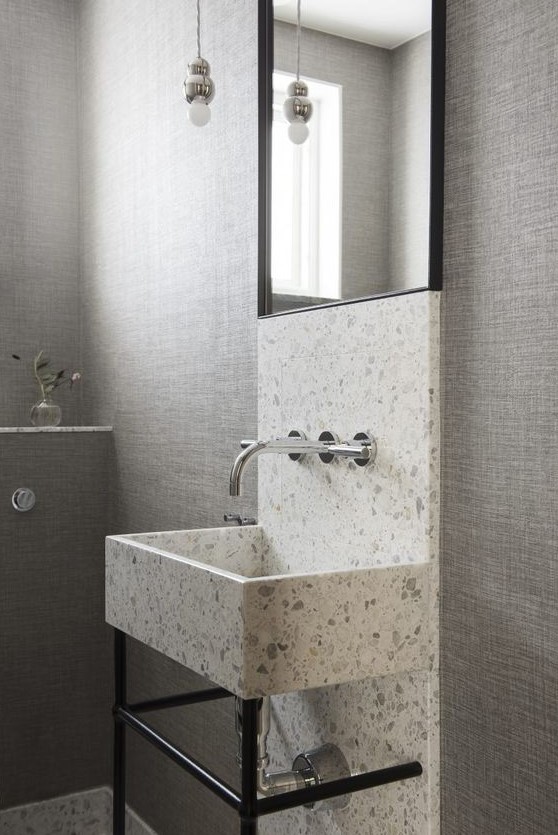 a white and grey terrazzo sink and a highlight along the wall brings interest and texture to the space