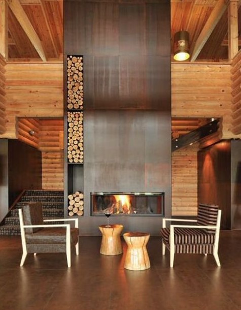 a woodland foyer with an oversized aged metal clad fireplace with niches for storing firewood is wow
