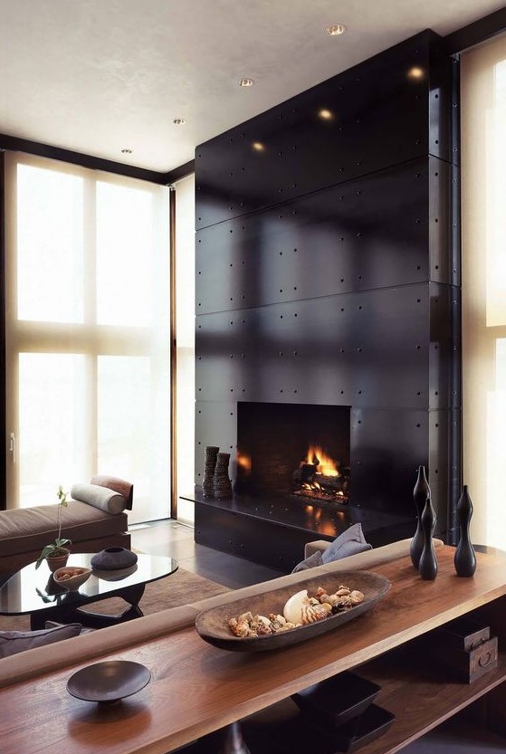 an exquisite living room with a large fireplace clad with black metal, neutral warm-colored furniture and black accents