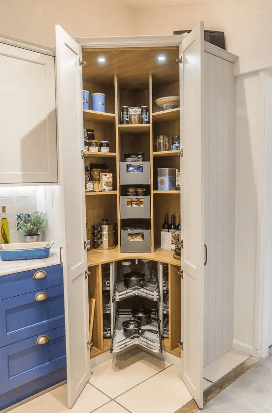 a small corner pantry with open shelves, drawers, built-in lights, cookware and groceries, some wine bottles