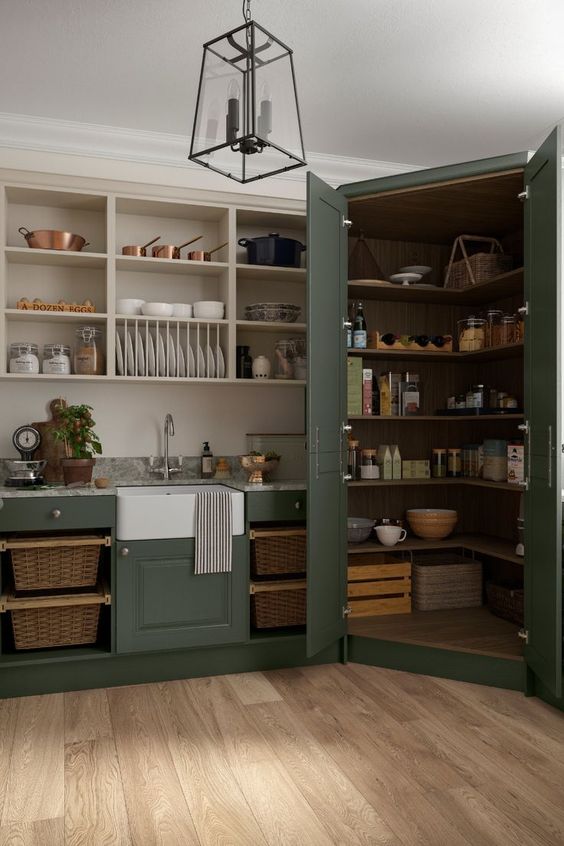A dark green vintage kitchen with open cabinets and a corner pantry that fits perfectly into the kitchen decor