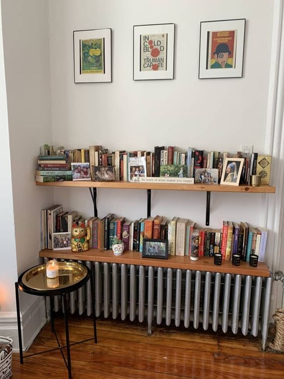 A metallic radiator with two stained bookshelves above it, one of which completely covers the radiator and makes it part of the decoration