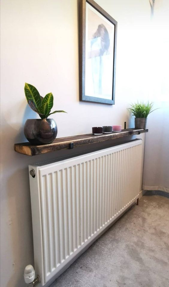 A narrow and long radiator with a dark stained shelf, candles and potted plants will look great in a modern room