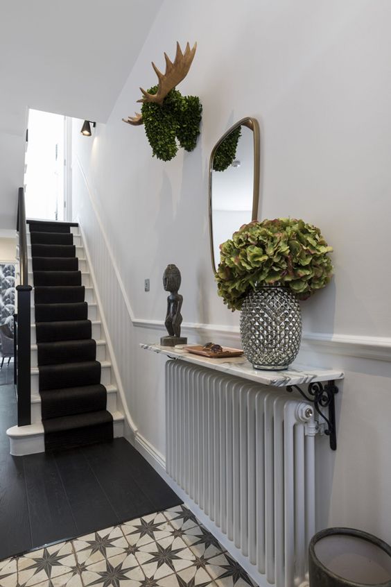 A radiator with a stone shelf above it, with decor and some greenery in a vase is a cool idea for a small entryway