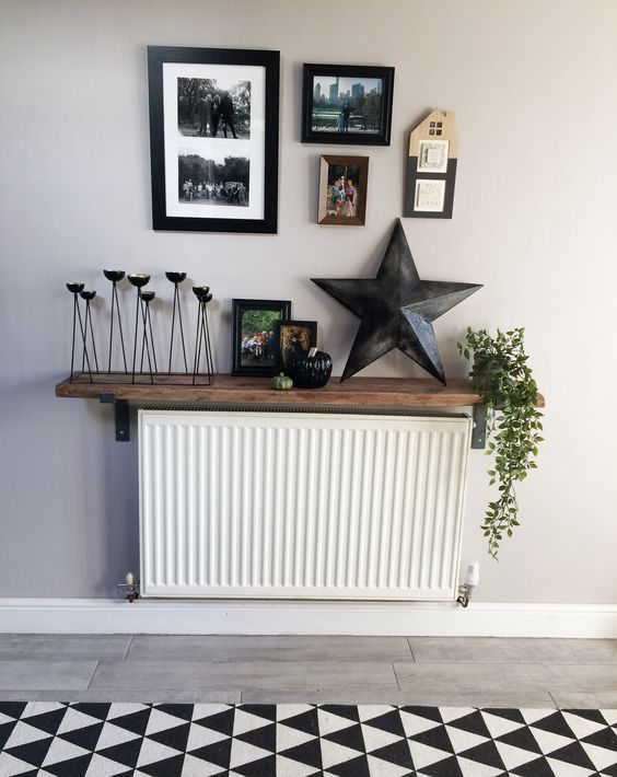 A Scandinavian room with a stained shelf above the radiator and some decoration, candle holders and green plants