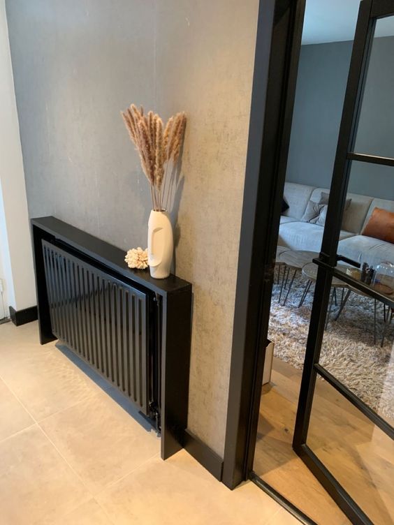 A small black radiator with a black shelf above it and some decor is a cool and beautiful idea