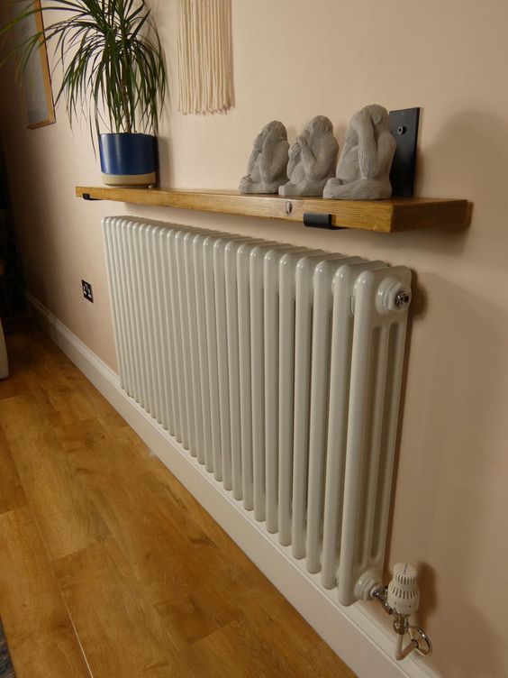 A small radiator with a stained shelf and decor on it is a beautiful combination for any boho or modern space