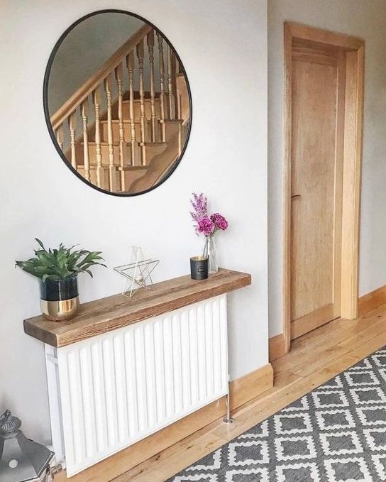 A white radiator with a stained shelf above it, with flowers, plants and decor is a cool idea for a Scandinavian room