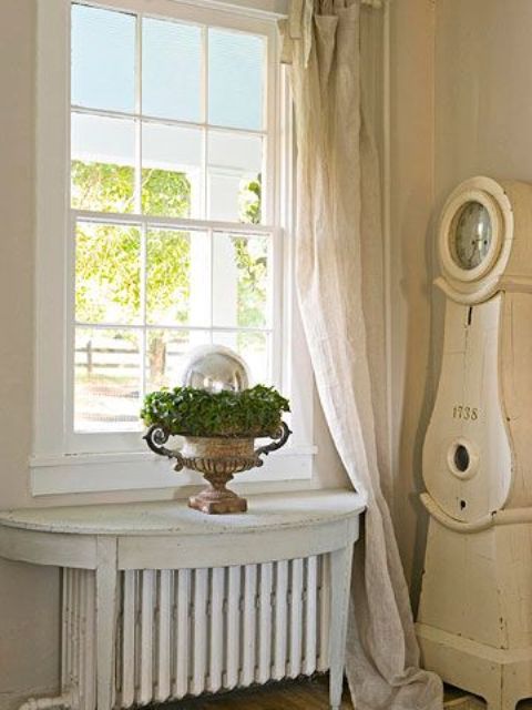 On the radiator there is an antique table with a worn white finish, transforming it into a comfortable shelf that can be used as a decoration