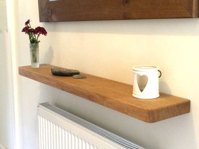 A stained oak floating shelf above a radiator is a cool idea for a hallway that is always short on storage space