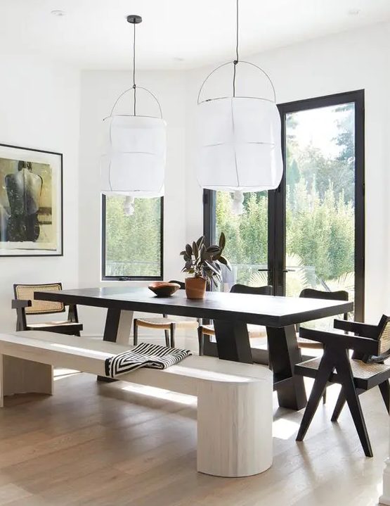 a bold dining area with a view, a black dining table and chairs, a whitewashed bench and a light stained floor