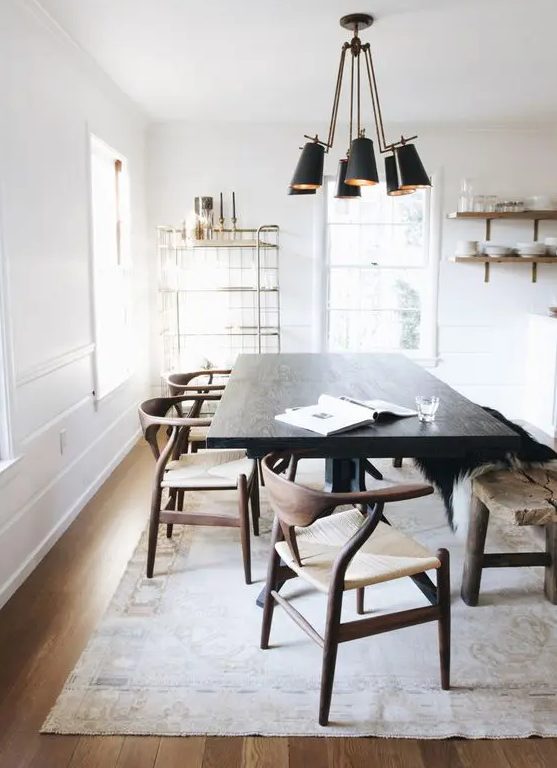 a light-filled dining area with a very dark stained table that makes a statement, richly stained chairs and a light stained floor, a black pendant lamp and open shelving