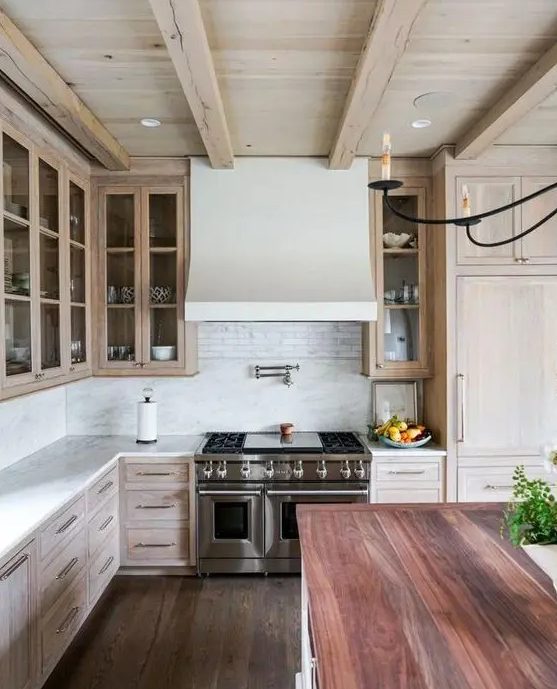 an attractive and inviting kitchen with a whitewashed ceiling and cabinets, a reclaimed wood floor and a kitchen island with a reddish countertop