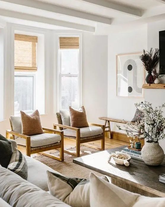 an elegant, neutral living room with a large sofa, white chairs with warm stained wood and a coffee table made from reclaimed wood for contrast