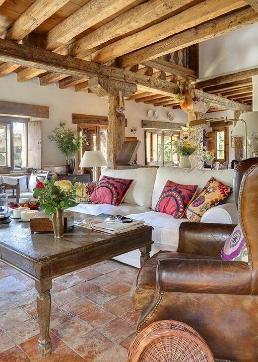 a rustic vintage living room with light stained wooden beams, a white sofa, leather armchairs and a dark stained coffee table