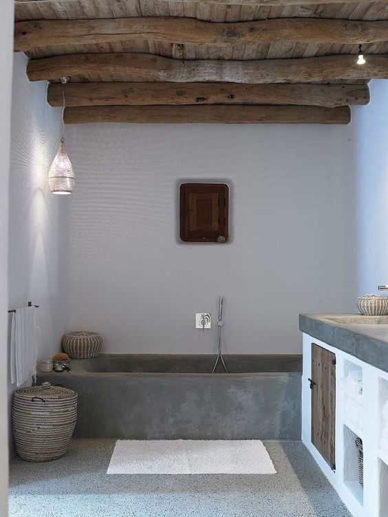 a modern bathroom with a concrete tub and terrazzo floor, a wooden ceiling with beams, a floating vanity with a concrete countertop