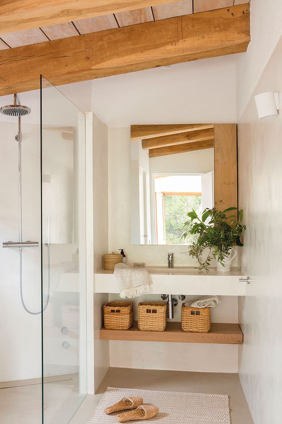 a neutral and inviting bathroom with wooden roof and beams, a built-in vanity and shelf, a shower area and a mirror