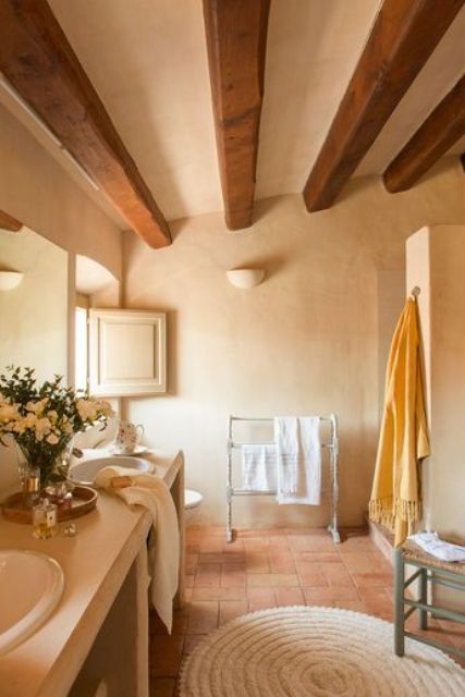 a neutral, warm bathroom with richly stained wooden beams, a double vanity, a shower area and some pretty textiles