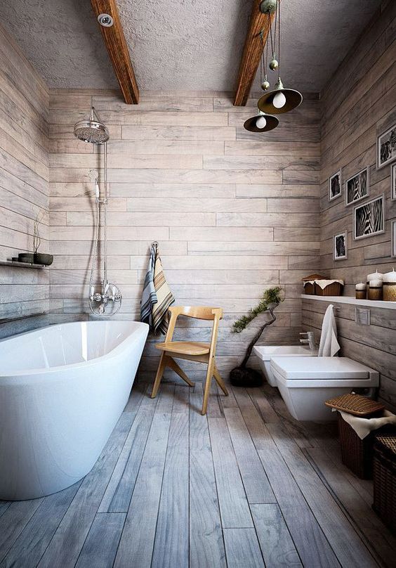 a rustic bathroom with weathered wood-look laminate flooring, wooden beams, a long open shelf and an oval bathtub, as well as hanging lamps